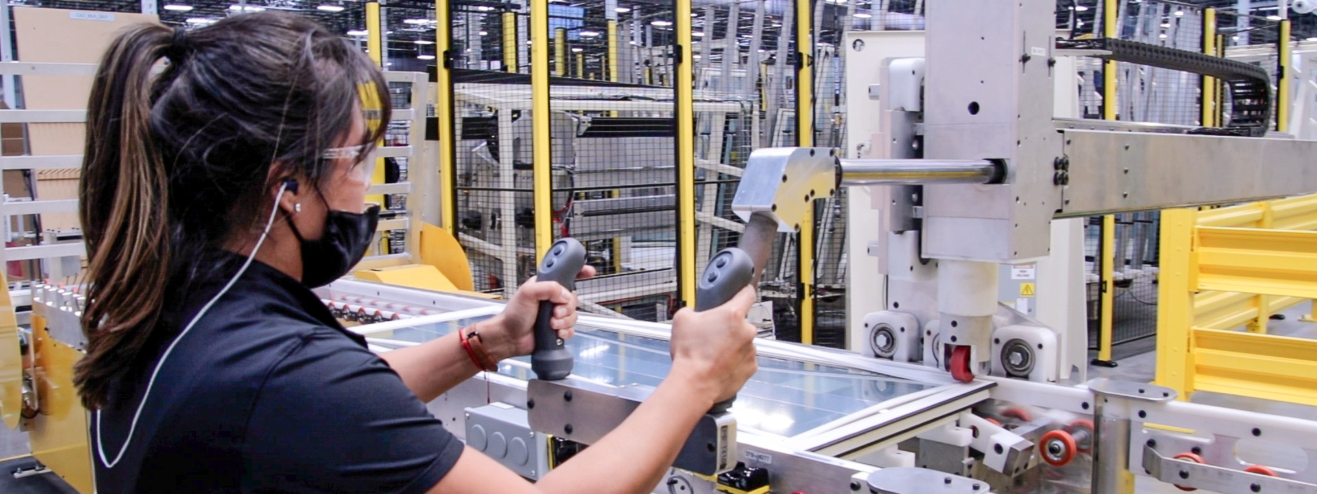 Manufacturing worker operating automated equipment on a production line inside a modern manufacturing facility.